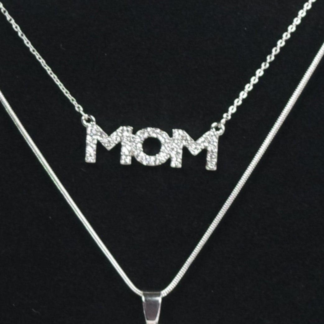 Necklace and earrings set with 'MOM' pendant on a black stand.