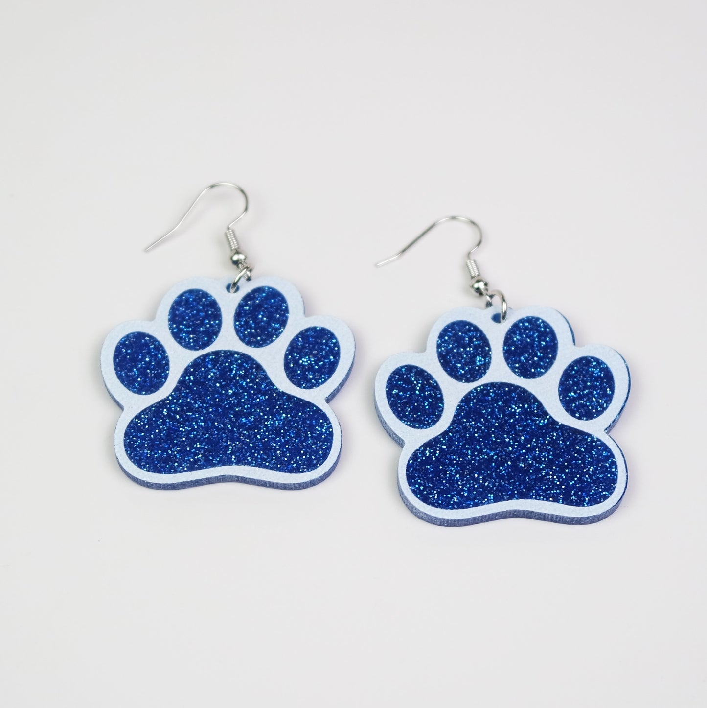 Blue glitter paw print earrings on a white background