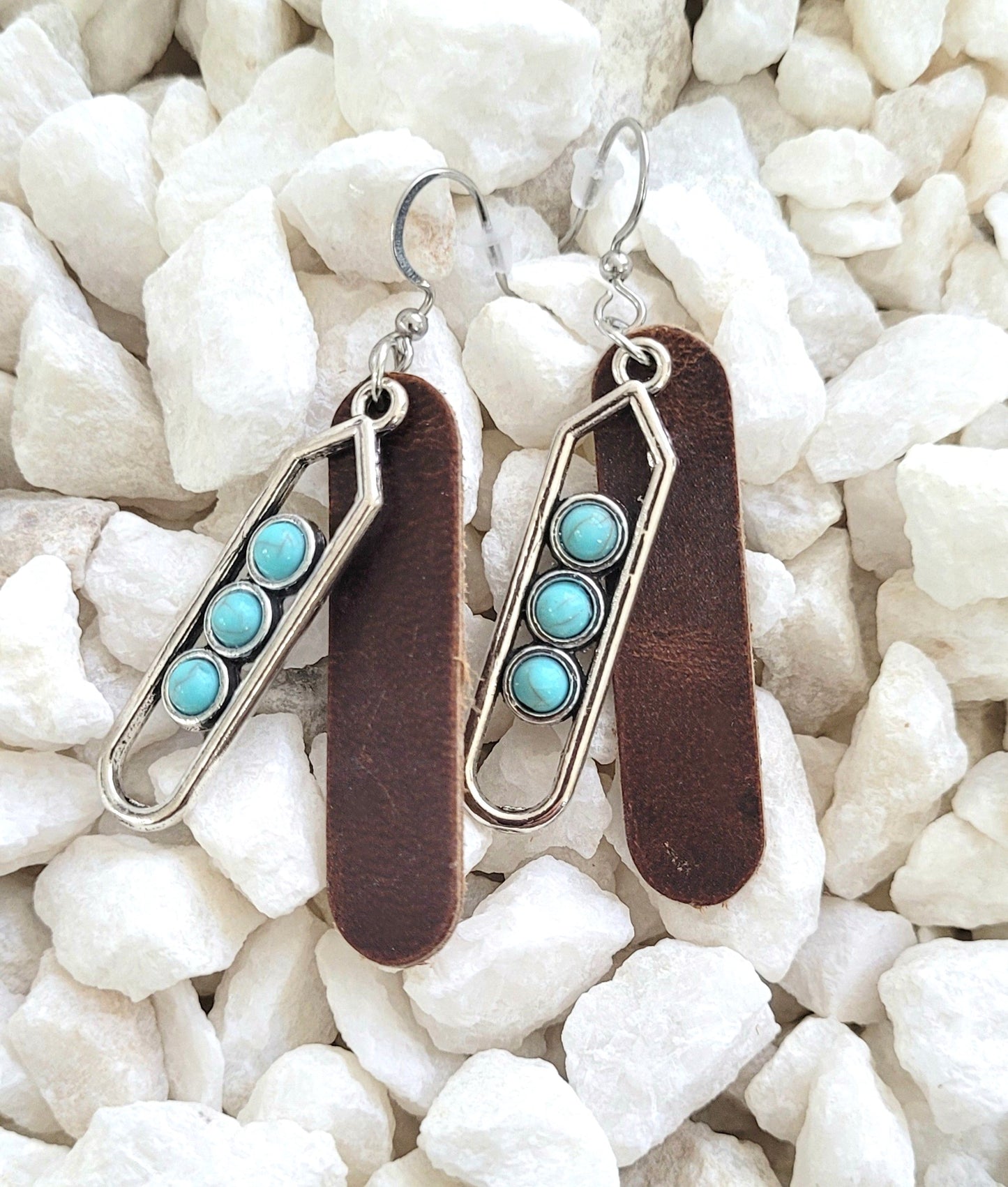 Pair of earrings with turquoise stones on a white stone background