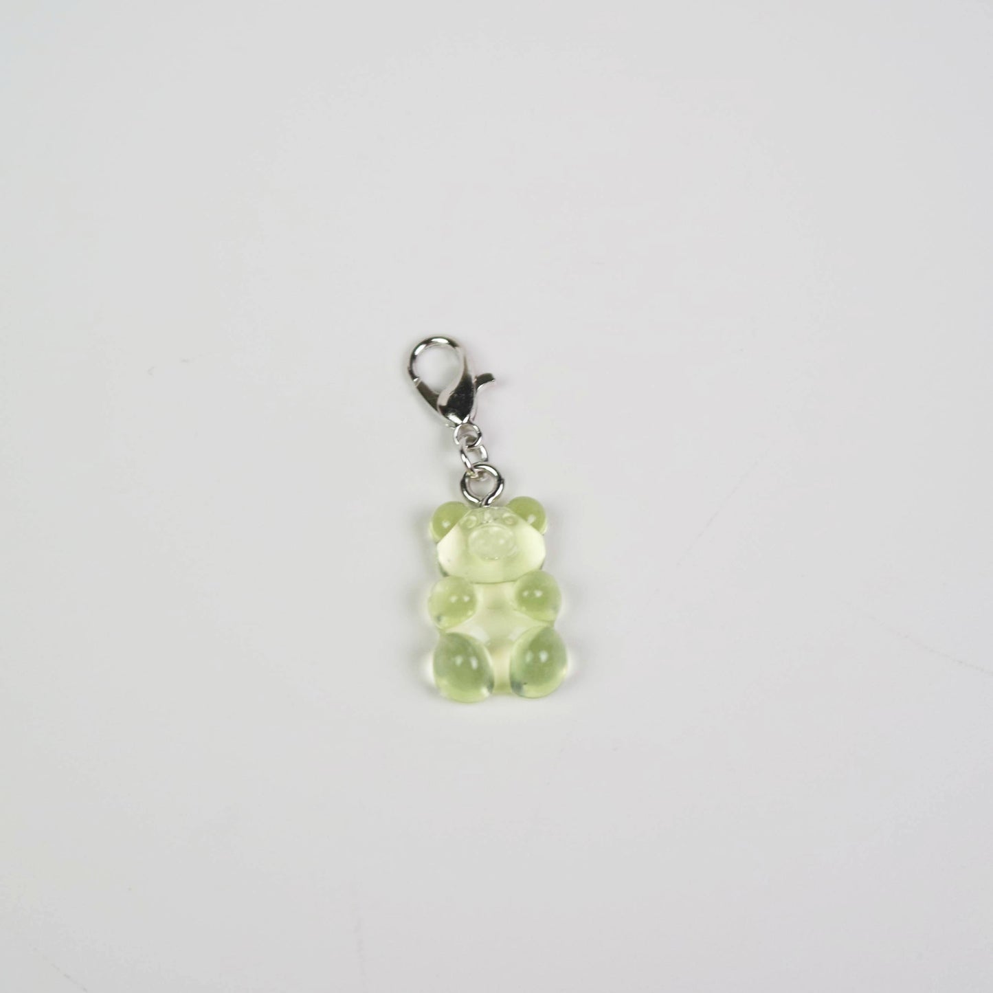 Green gummy bear charm on a white background