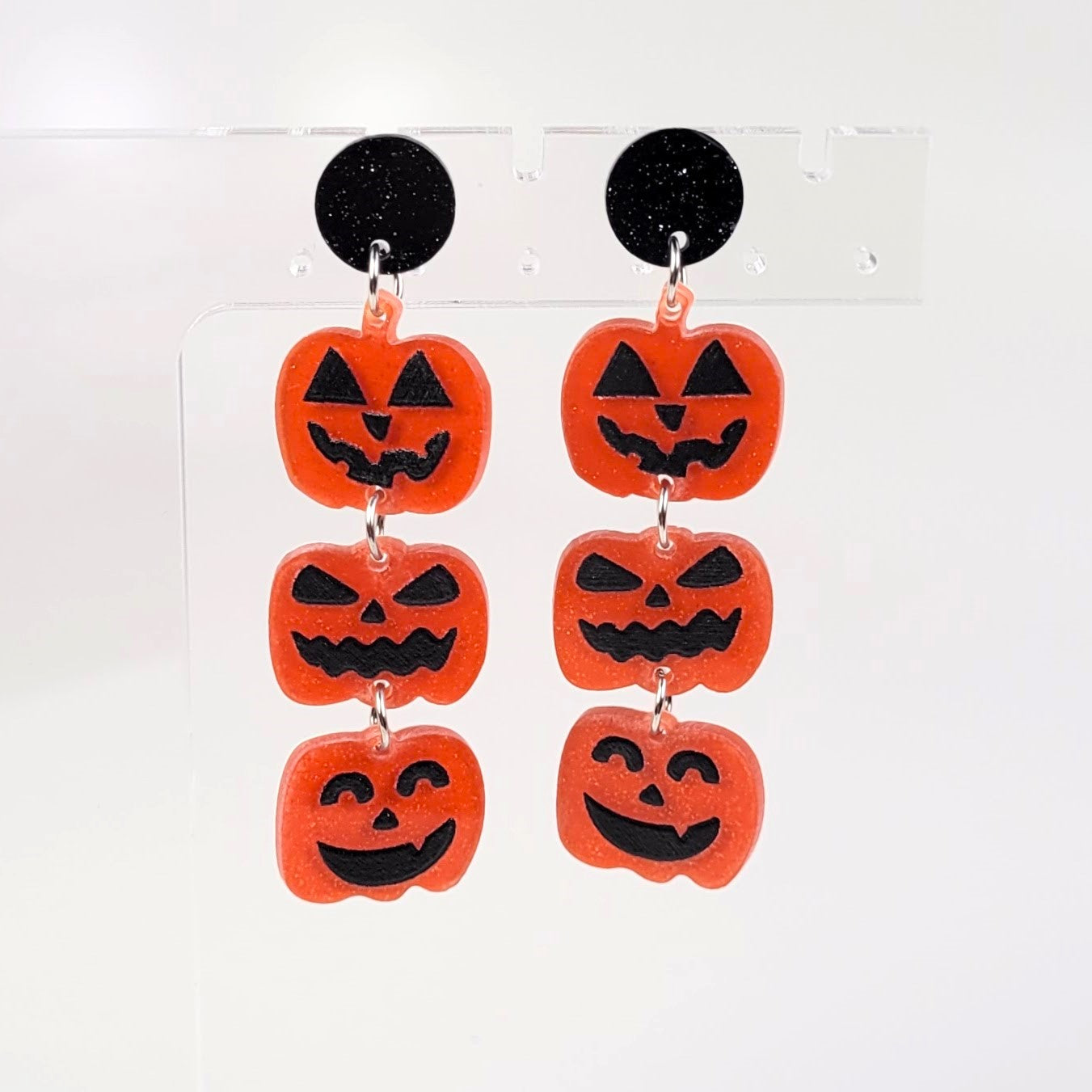 Halloween-themed earrings with jack-o'-lantern faces on a white background