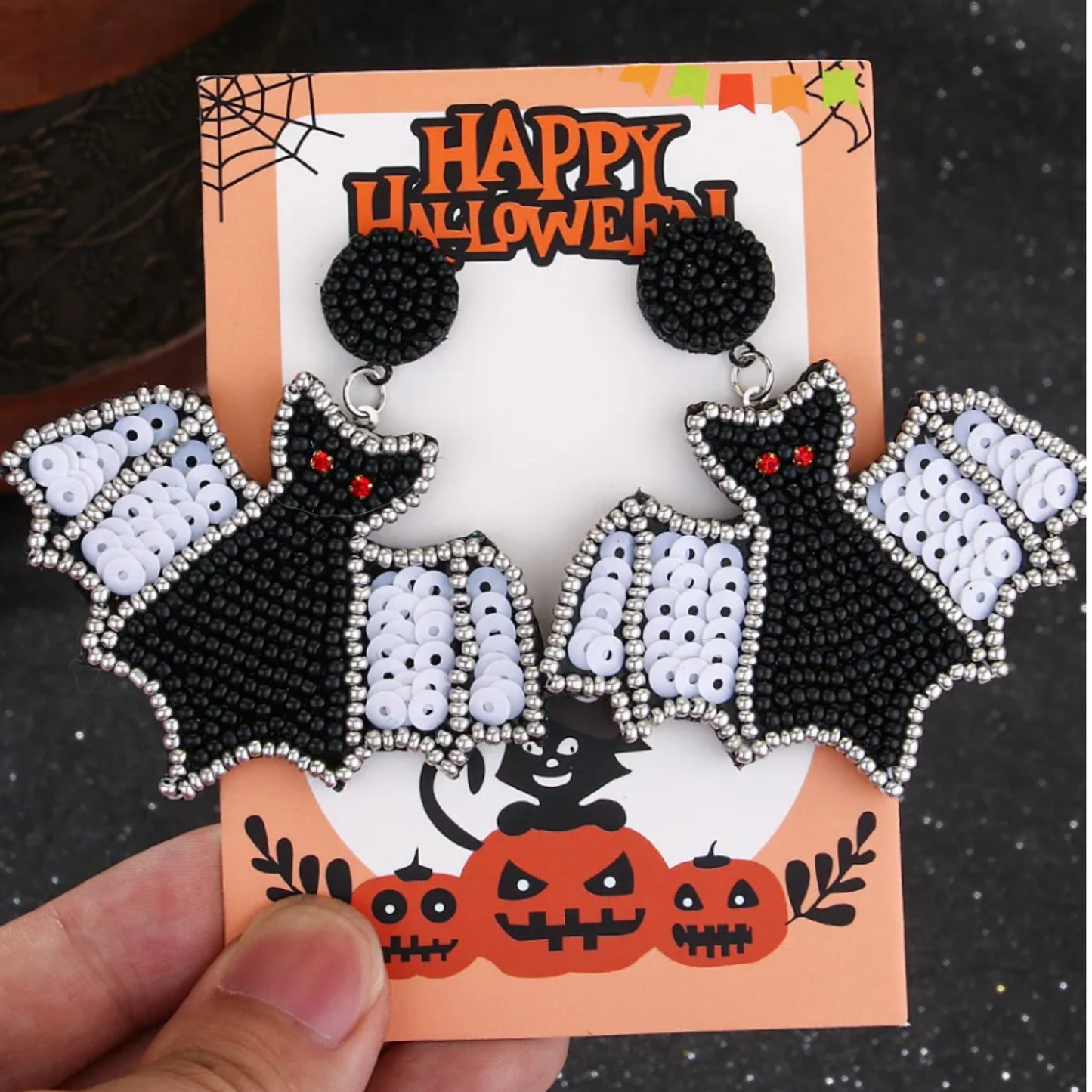 Halloween-themed beaded earrings on a decorative card with pumpkins and spider webs.