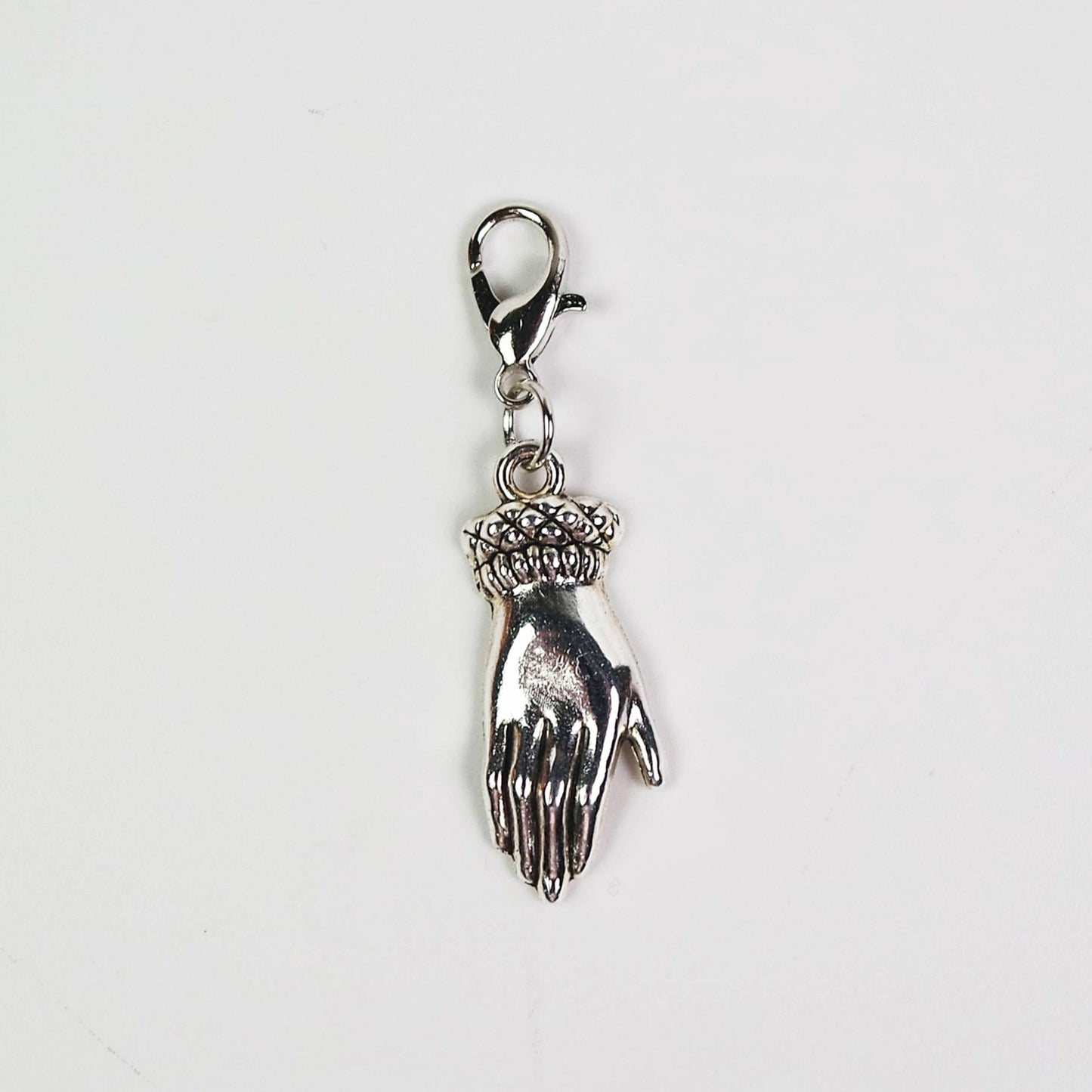 Silver charm of a hand on a white background