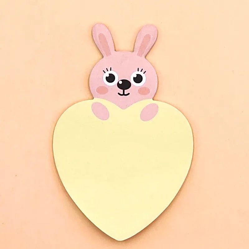 A pink cartoon bunny rabbit with a heart-shaped notepad in its hands, set against a beige background.