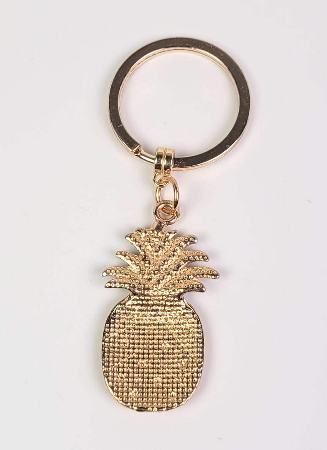 Gold pineapple keychain on a white background