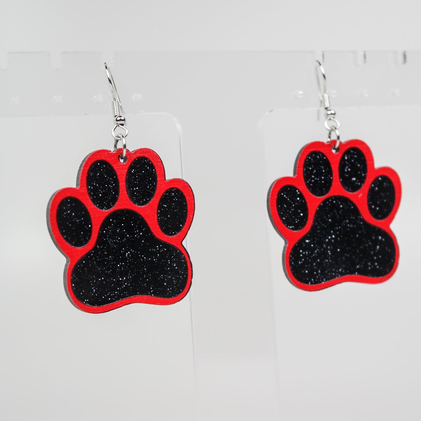 Red and black paw print earrings on a white background