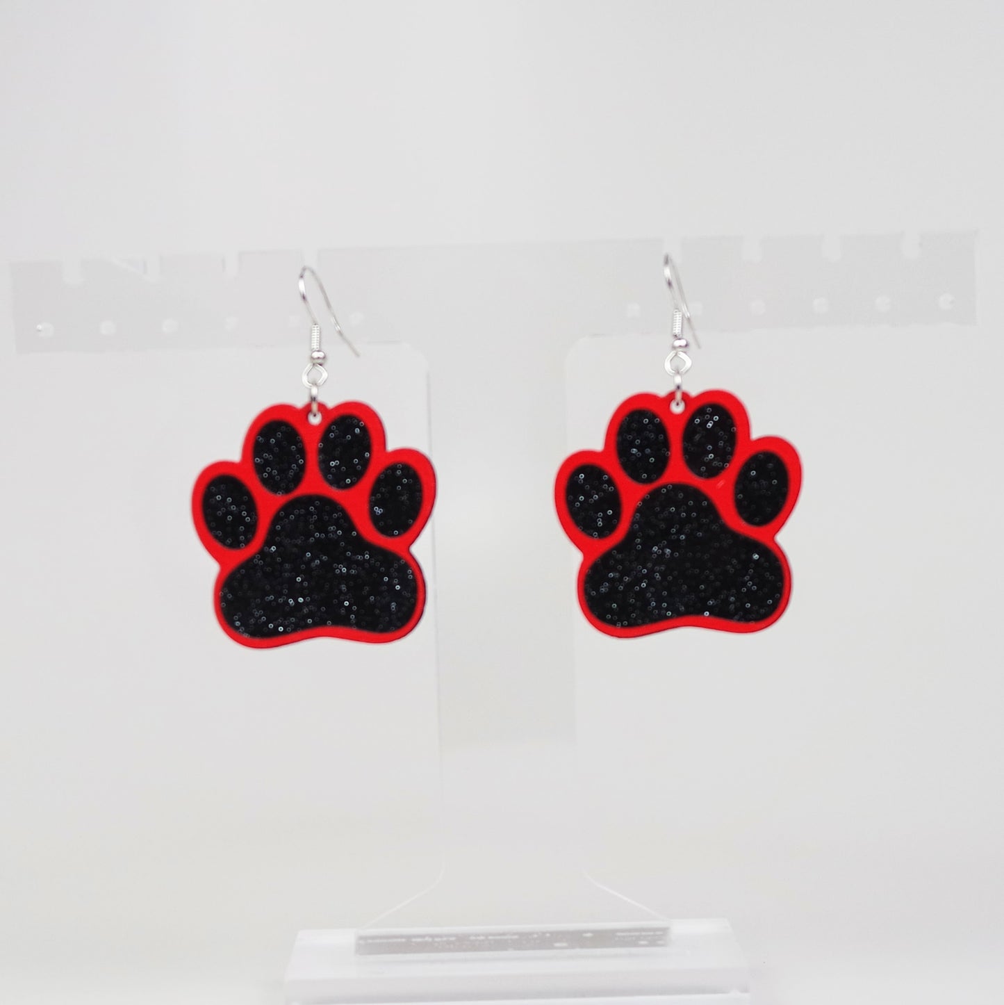 Paw print earrings with red and black design on a clear background