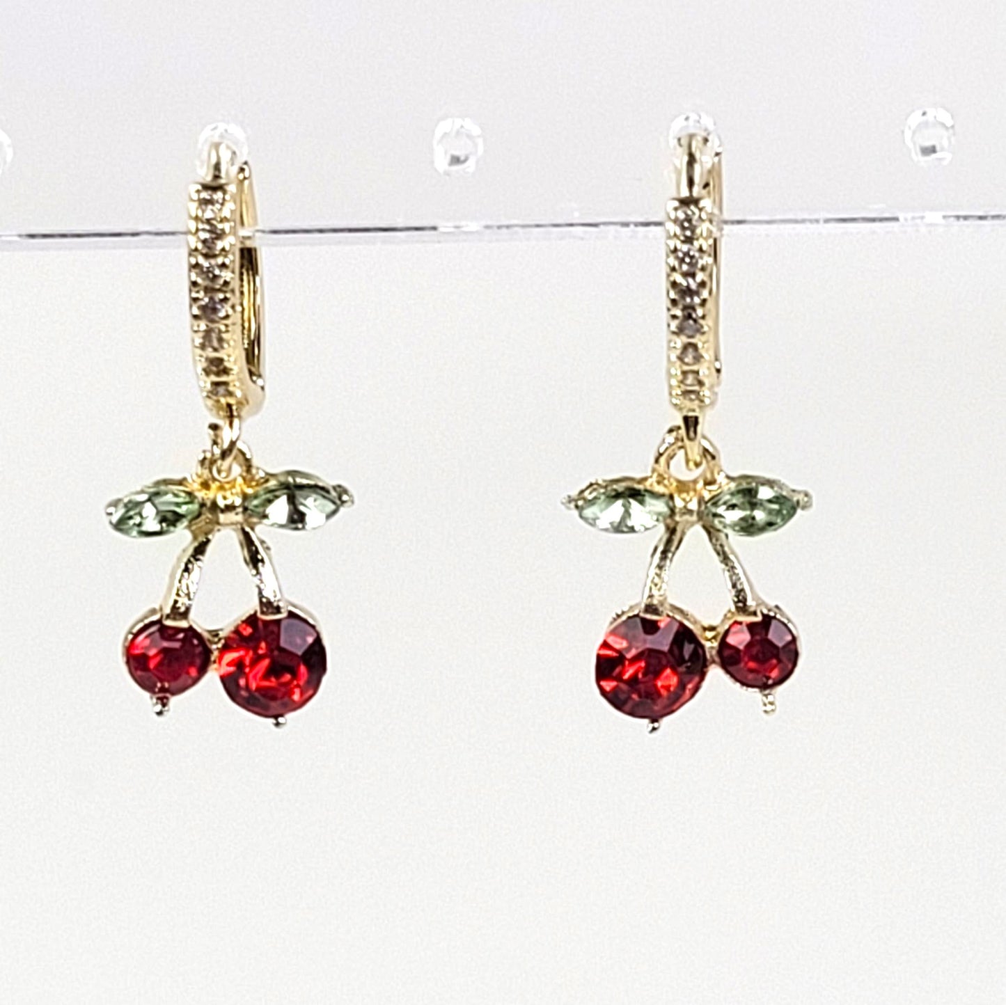 Cherry-themed earrings with red gemstones and gold accents on a white background