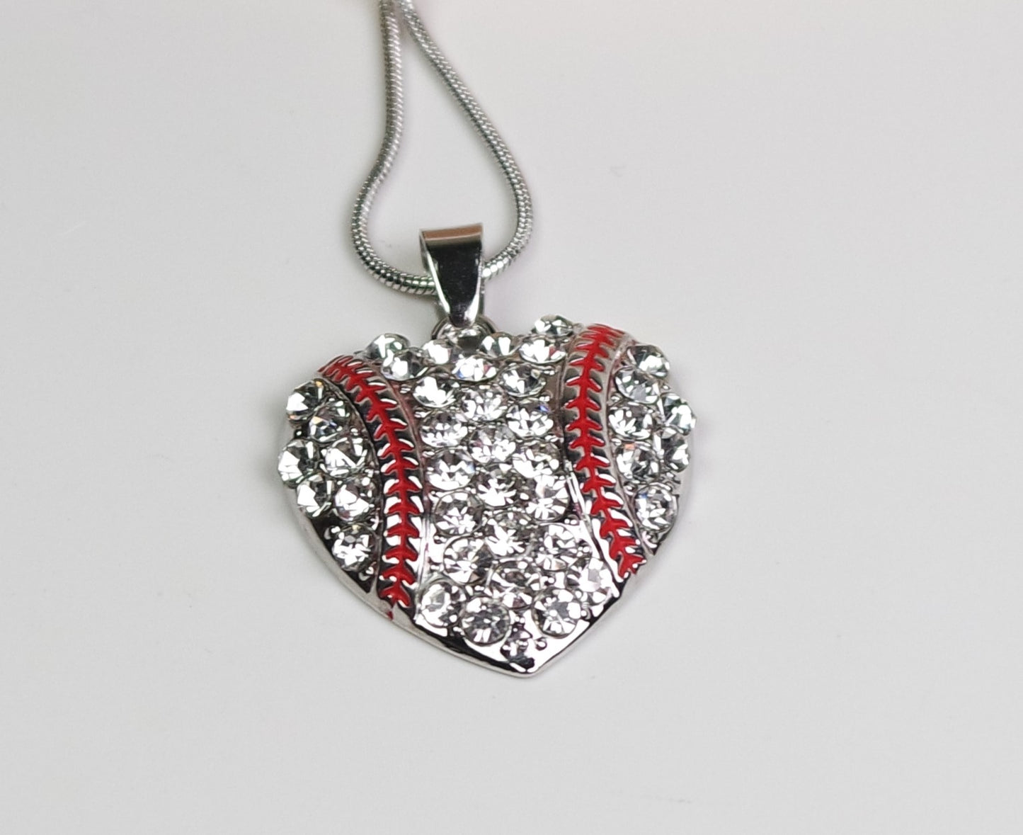 Heart-shaped pendant with rhinestone detailing on a gray background