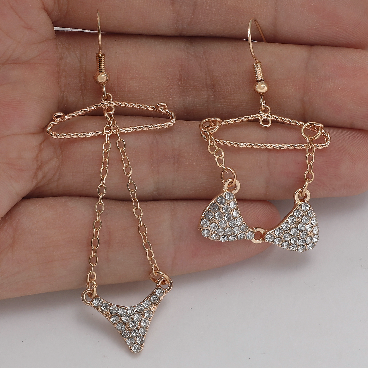 Hand Holding mismatched dangle earrings with hangers holding each piece of bikini
