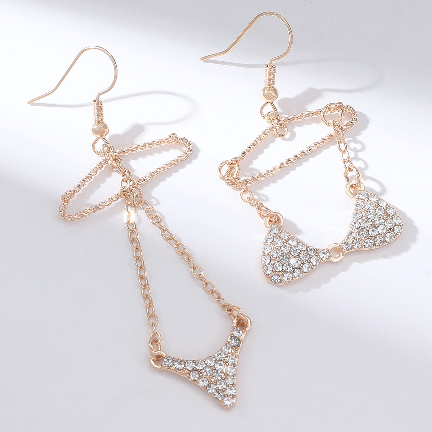 A pair of gold-tone mismatched dangle earrings featuring a rhinestone bikini design on wire hangers.