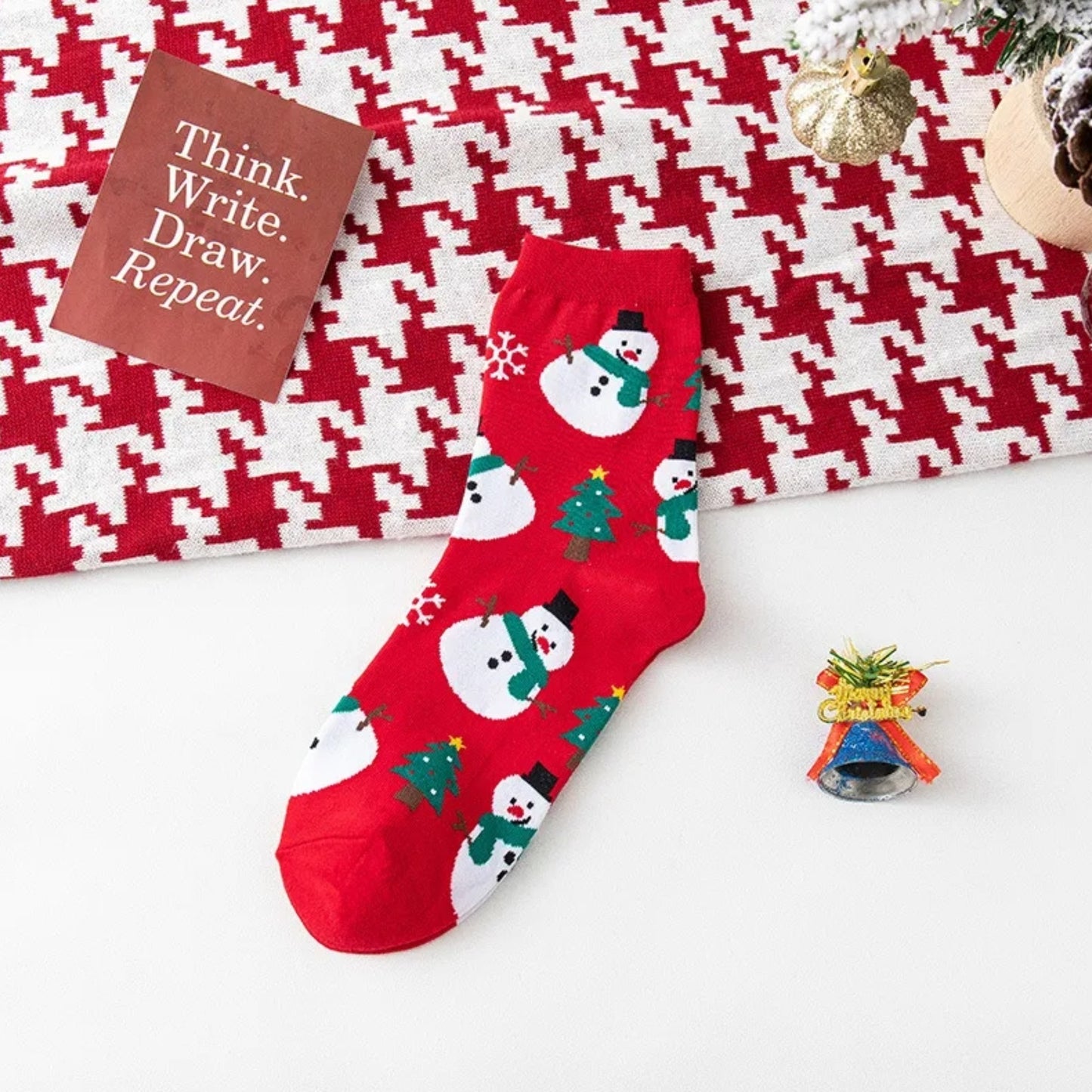 Red socks with snowman and tree pattern on a white and red checkered background