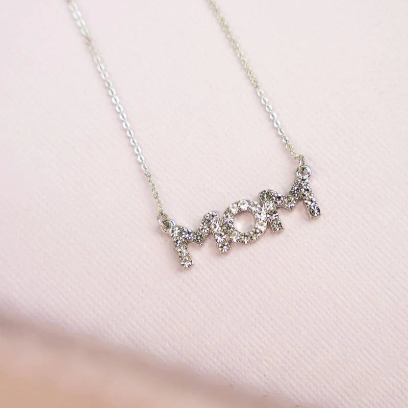 A silver-tone necklace with the word 'MOM' written in rhinestones.