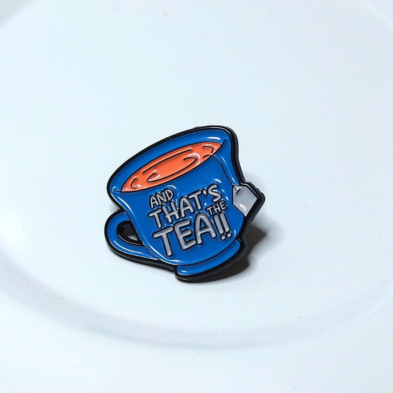 Enamel pin shaped like a teacup with text on a white background