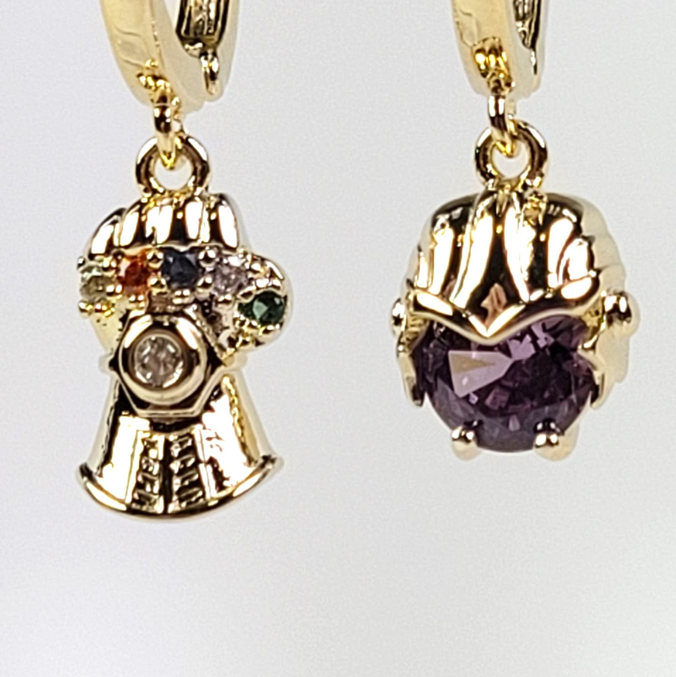 Gold earrings with gemstones on a light gray background