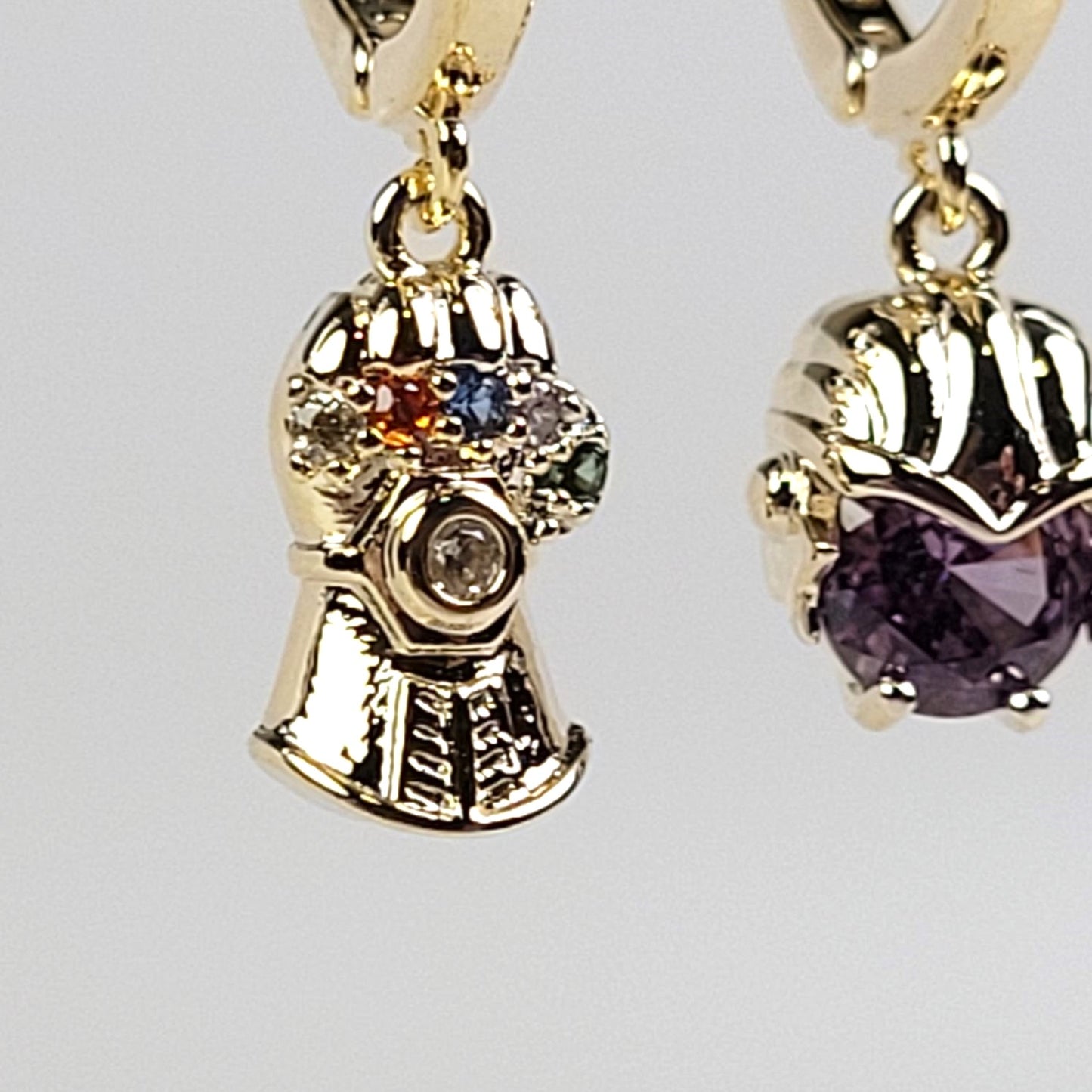 Gold earrings with gemstones on a light gray background