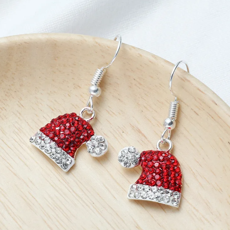 Red and silver Santa hat earrings on a wooden surface