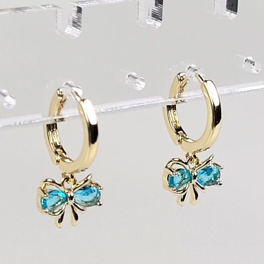 Gold hoop earrings with blue gemstones on a clear background