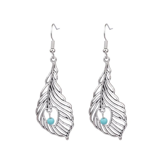 A pair of silver dangle earrings with abstract feather designs and turquoise bead insets.