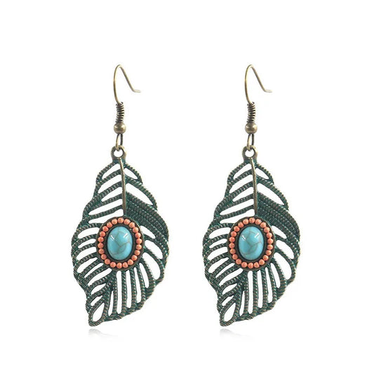 A pair of Bohemian style drop earrings featuring a hollow feather design with bead inlay and a green antique finish.