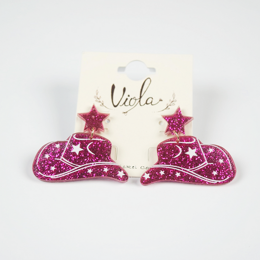 Pink glittery cowboy hat earrings on a 'Viola' branded card against a white background