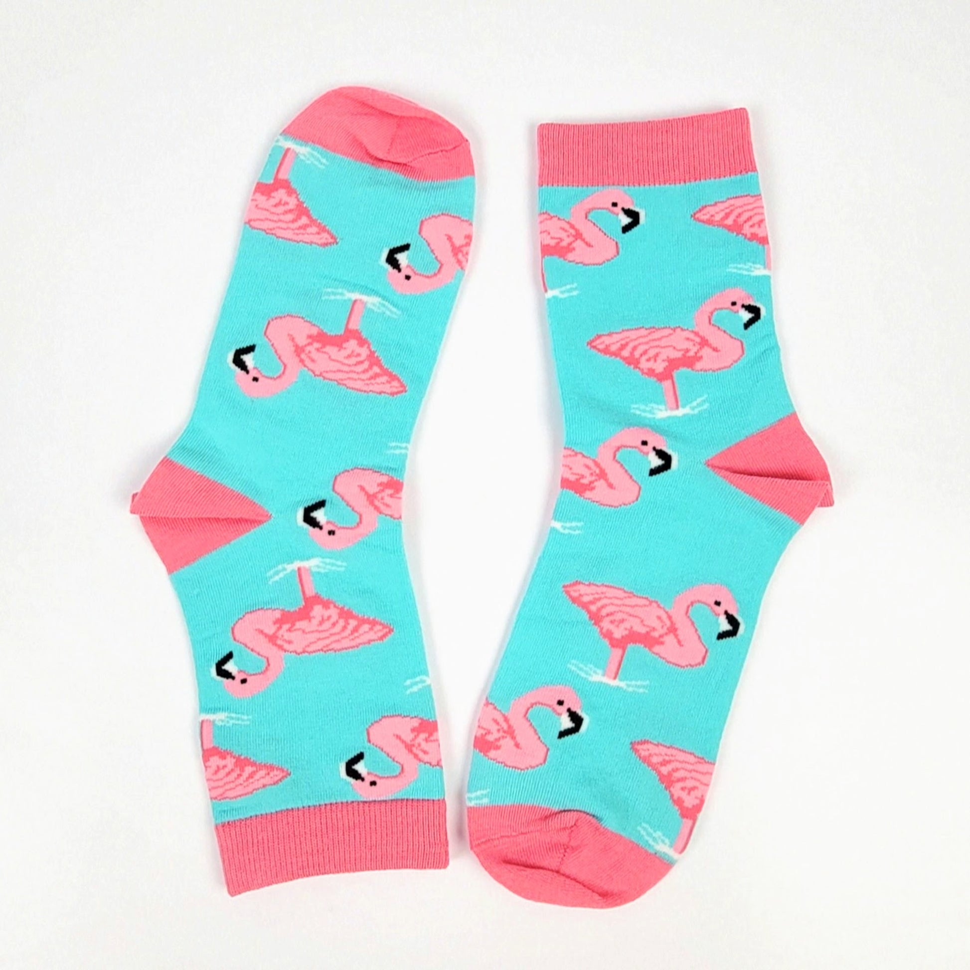 A pair of ladies crew socks with a pattern of pink flamingos in aqua water, with pink accents on the cuffs.