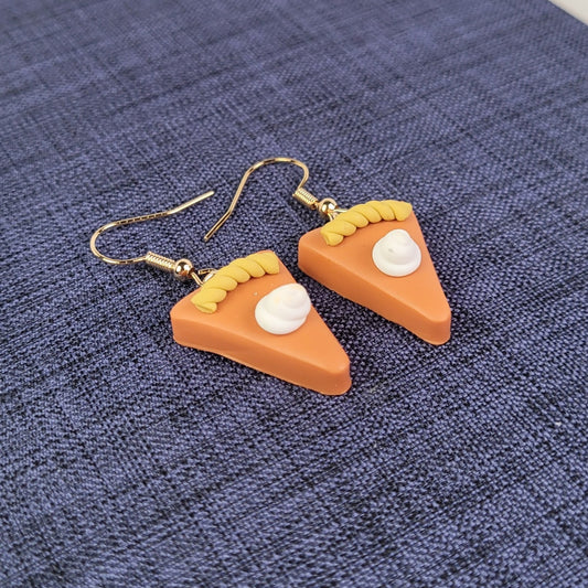 Pumpkin pie slice earrings on a blue textured fabric background