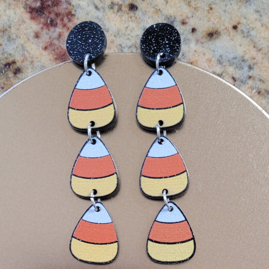 Colorful layered teardrop earrings on a beige card with a brown background