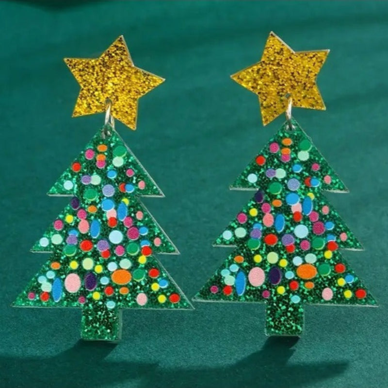 Christmas tree-shaped earrings with colorful dots and gold star tops on a green background