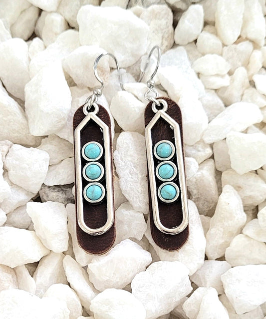 Pair of earrings with turquoise stones on a white pebble background