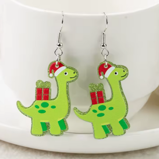 Green dinosaur earrings with red hats and gift boxes on a white surface