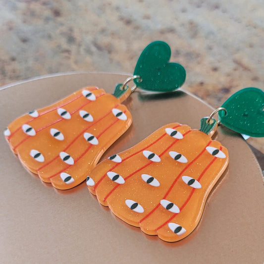 Pumpkin-shaped earrings with green Hearts on a beige background