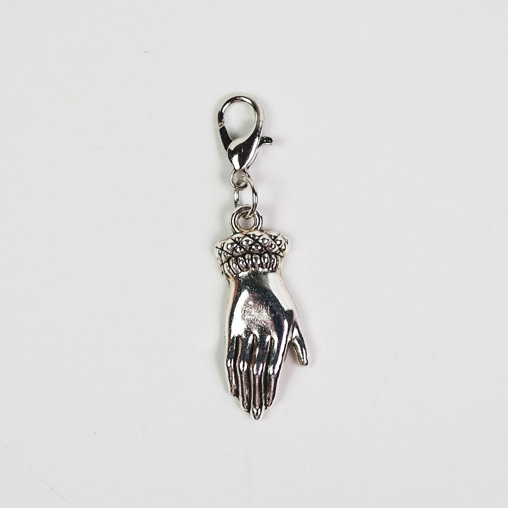 Silver charm of a hand on a white background