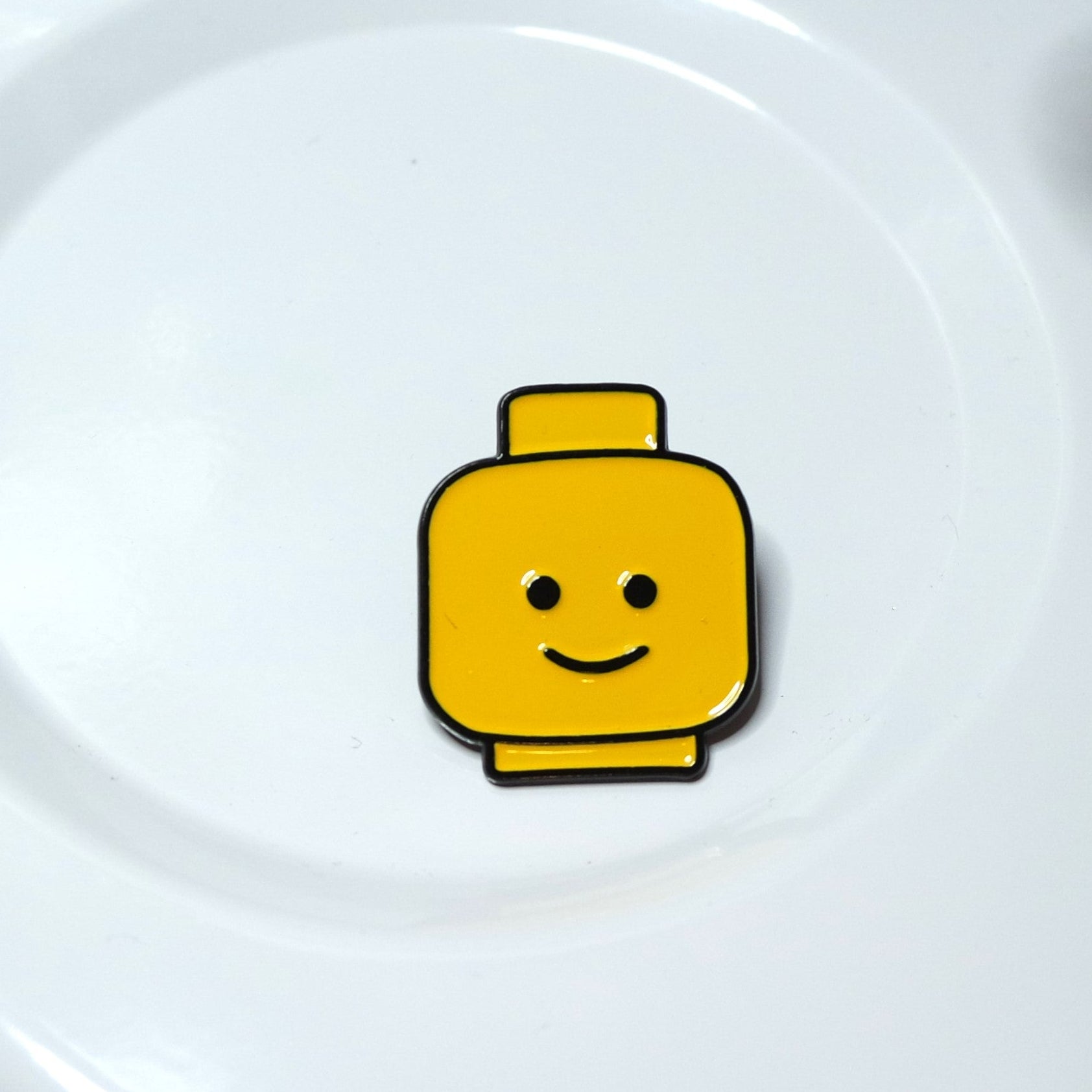 Yellow Lego-style head charm on a white background