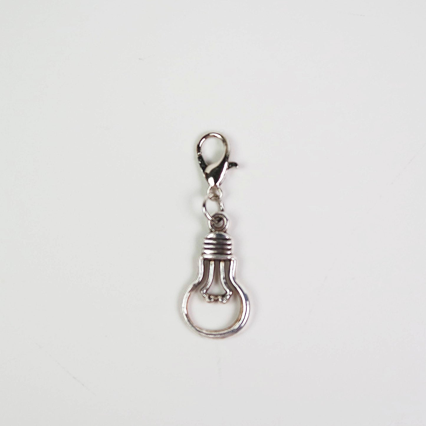 Silver light bulb-shaped keychain charm on a white background