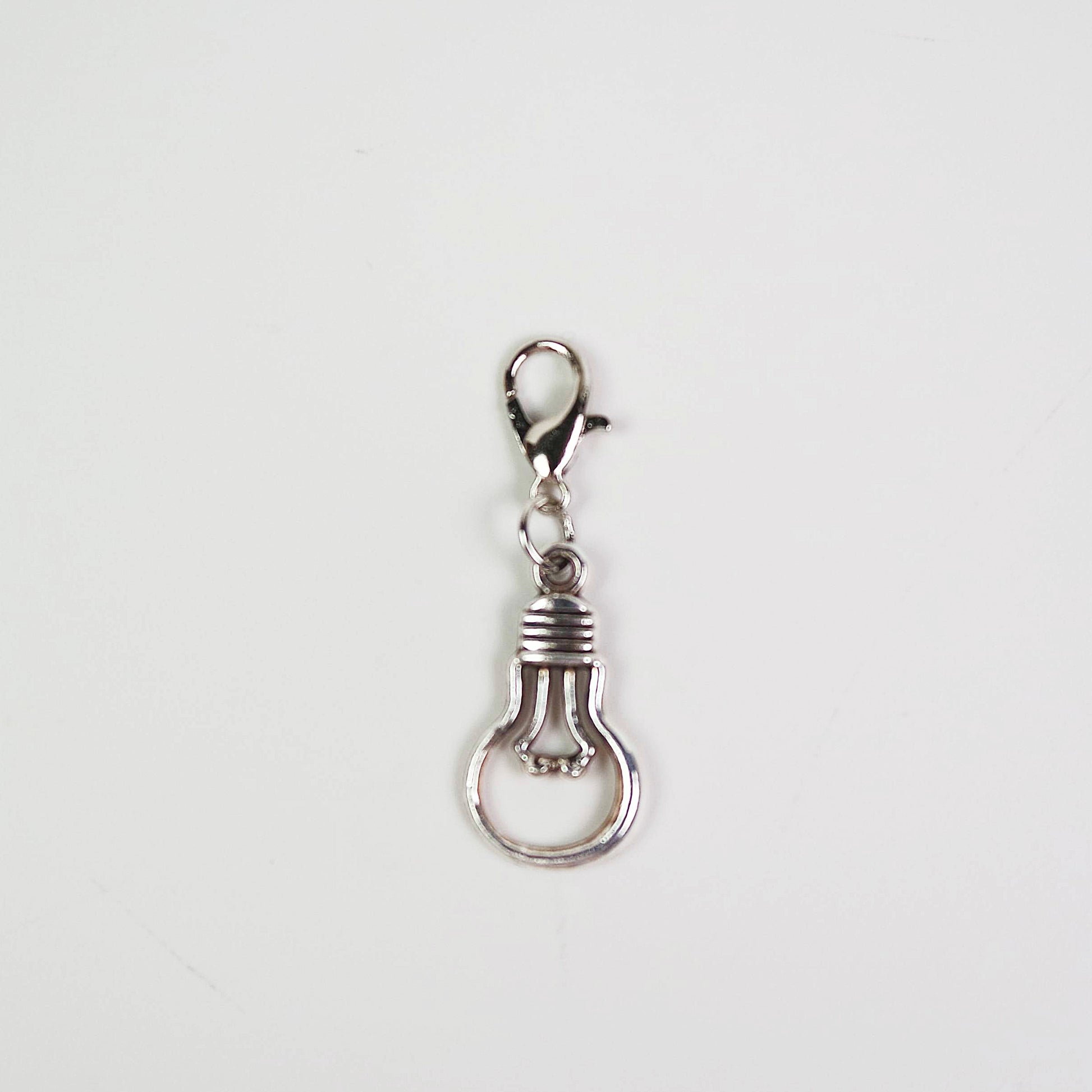 Silver light bulb-shaped keychain charm on a white background