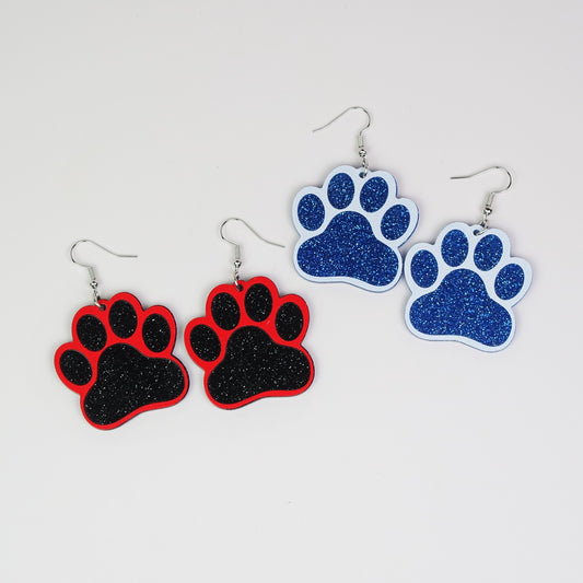 Paw print earrings in red, black, and blue on a light gray background