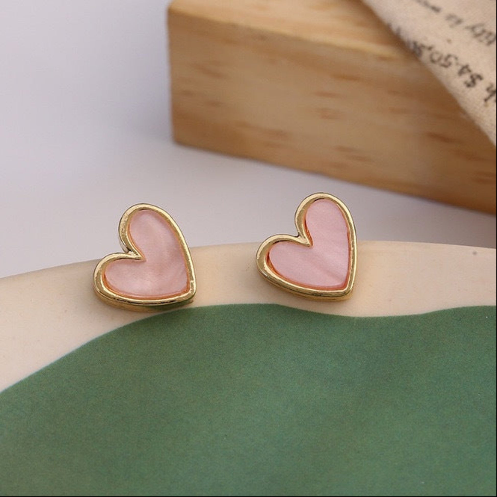 Gold Tone Metal Heart Shaped Stud Earrings With Pink Swirl Inlay  on colorful background