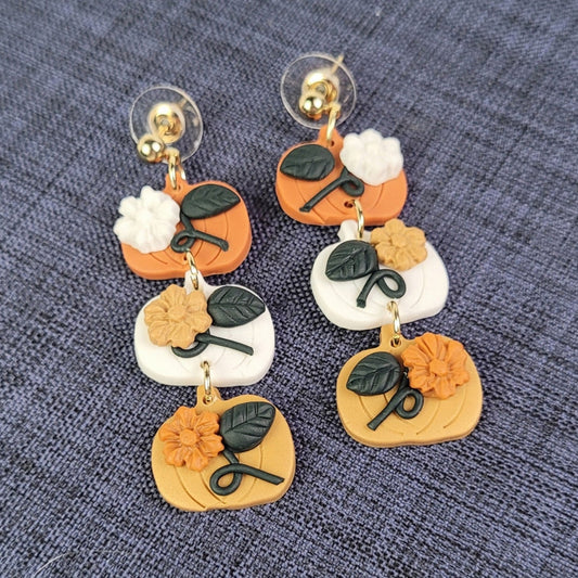 Pair of floral-themed earrings on a textured blue background