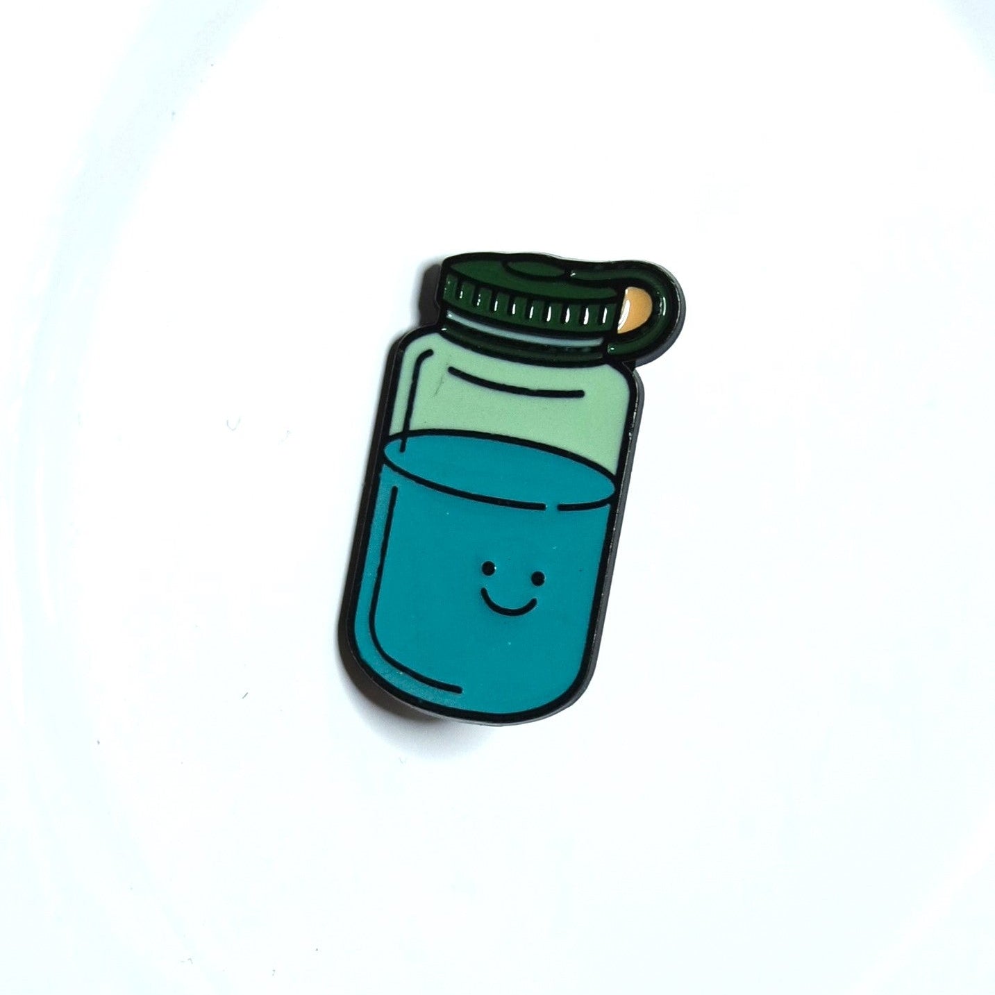 Enamel pin of a bottle with blue liquid on a white background