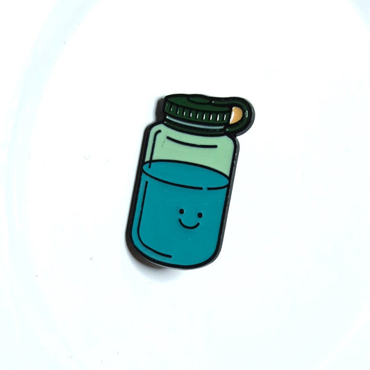 Enamel pin of a bottle with blue liquid on a white background