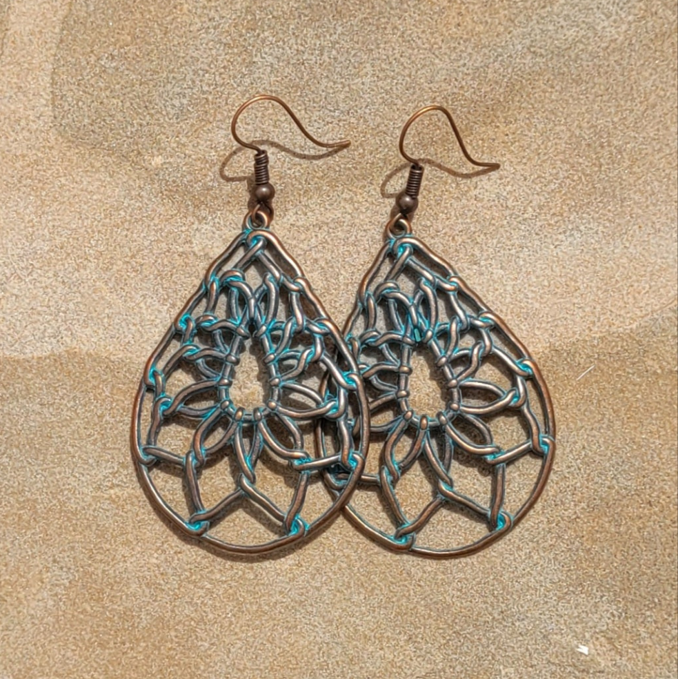 Pair of brass and turquoise earrings on a beige background