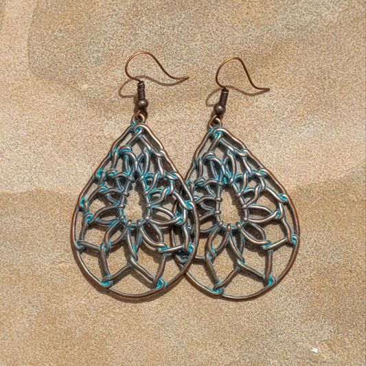 Pair of brass and turquoise earrings on a beige background