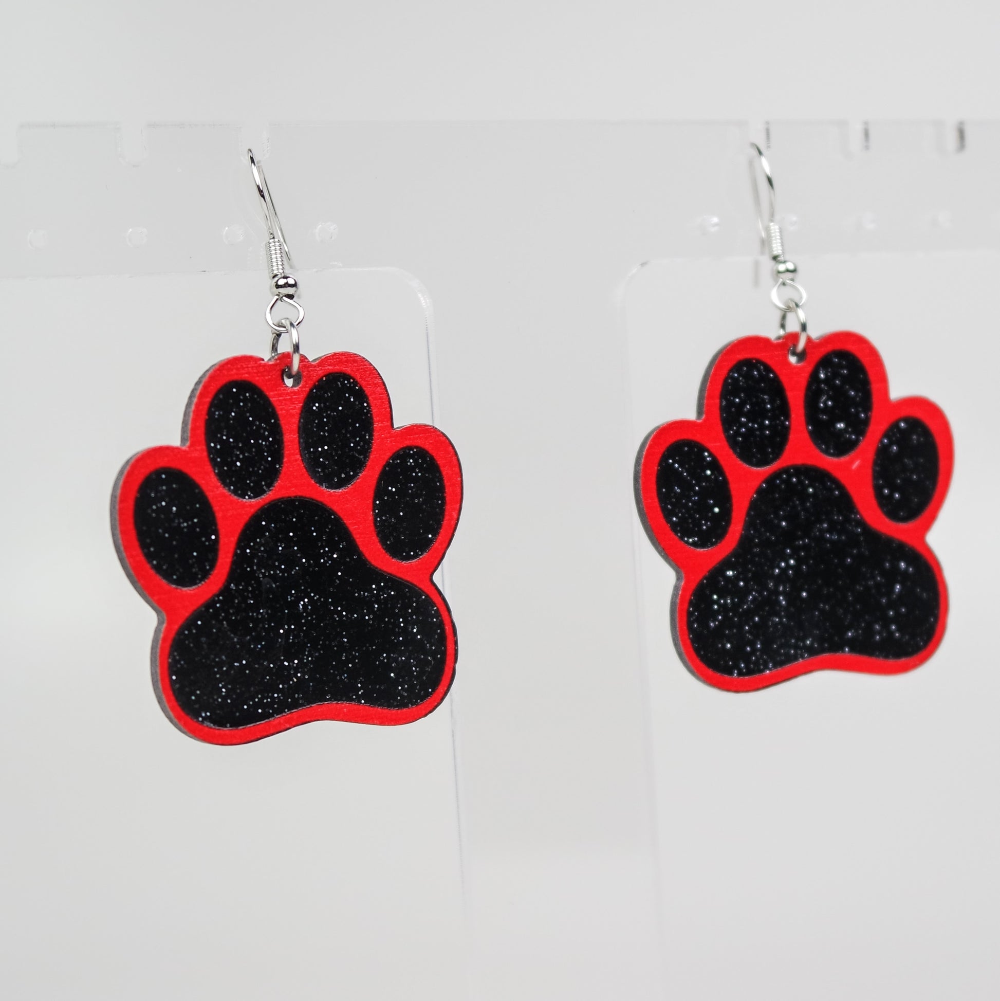 Red and black paw print earrings on a white background