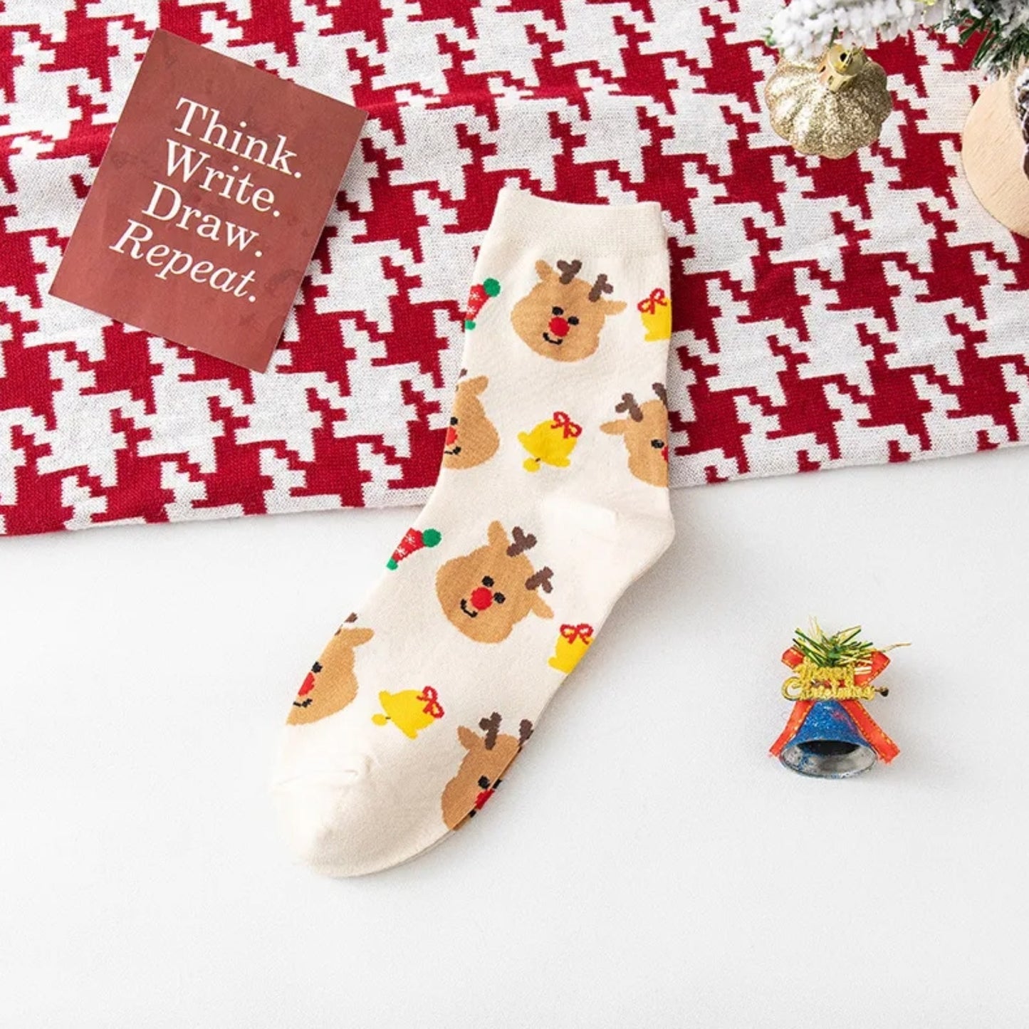 Socks with reindeer pattern on a white surface with a red and white checkered fabric in the background.