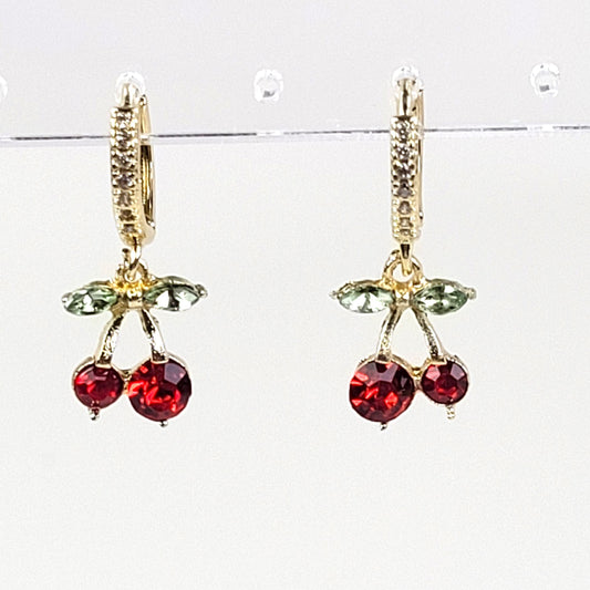 Cherry-themed earrings with red gemstones and gold accents on a white background