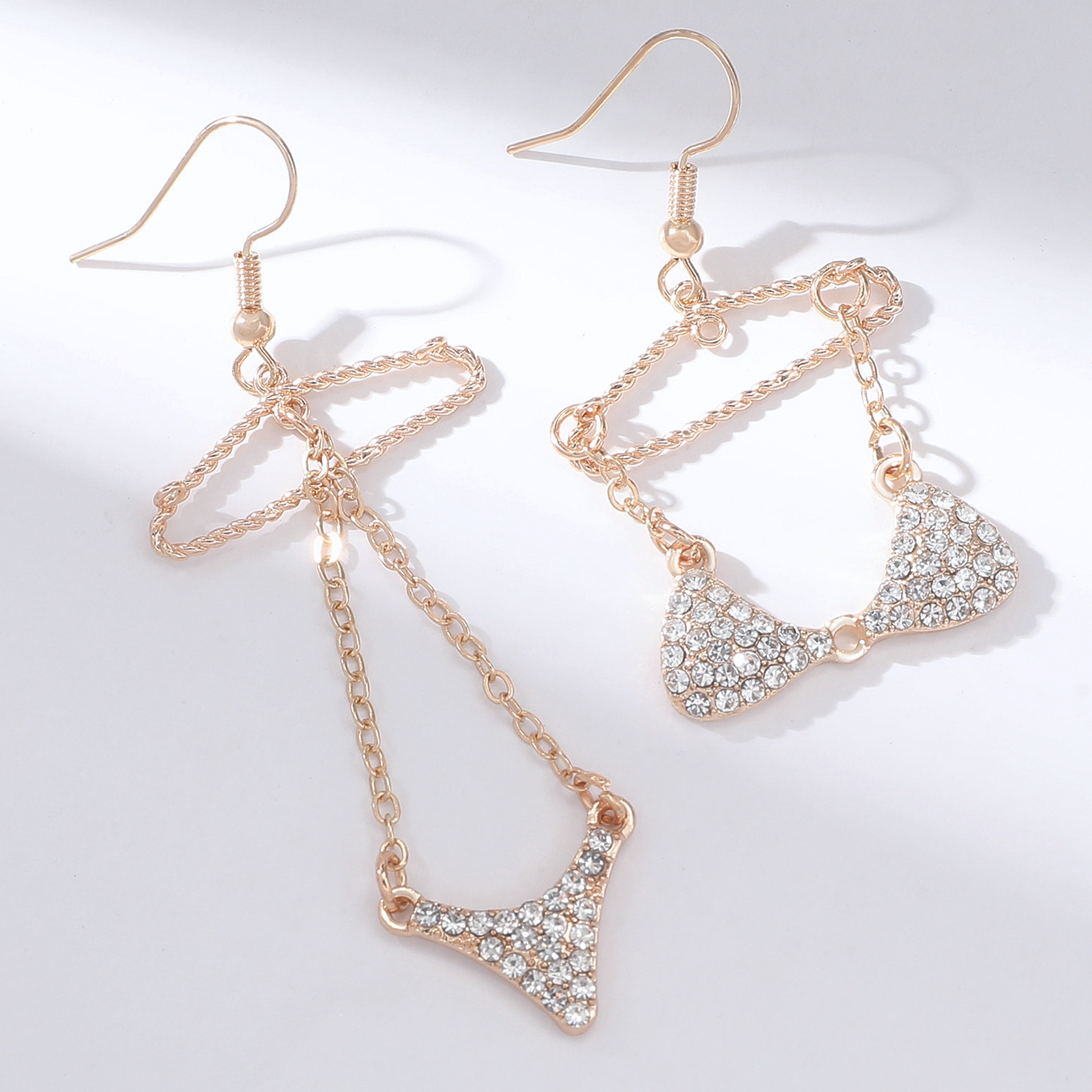 A pair of gold-tone mismatched dangle earrings featuring a rhinestone bikini design on wire hangers.