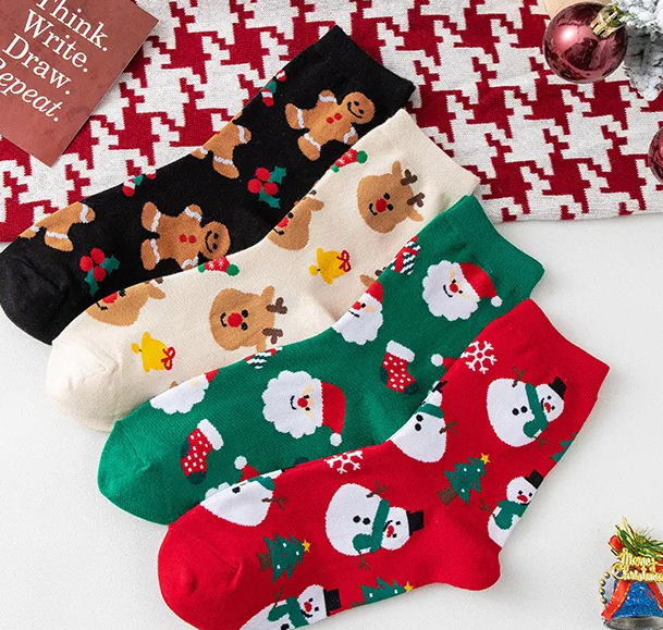 Four pairs of Christmas-themed socks with gingerbread men, reindeer, Santa Claus, and snowmen on a patterned background.