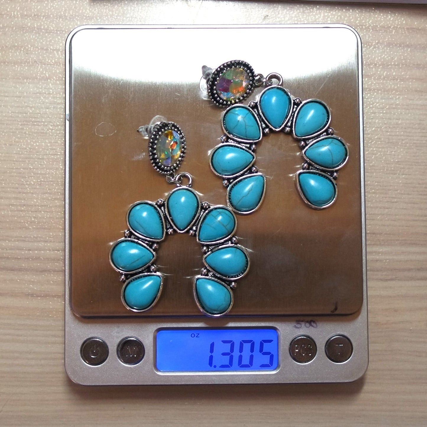 Turquoise earrings on a digital scale displaying weight