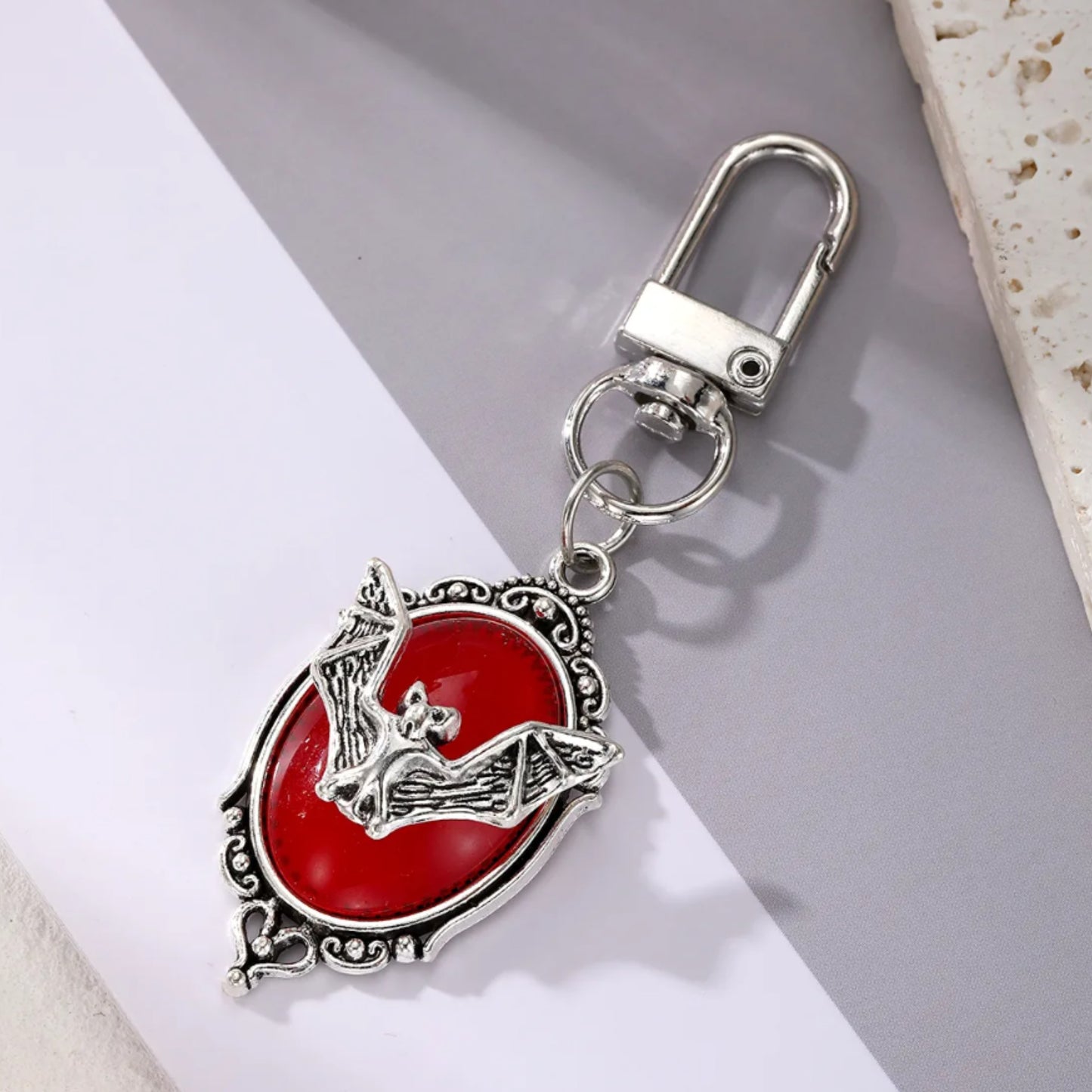 Keychain with red circular design and silver accents on a light gray background
